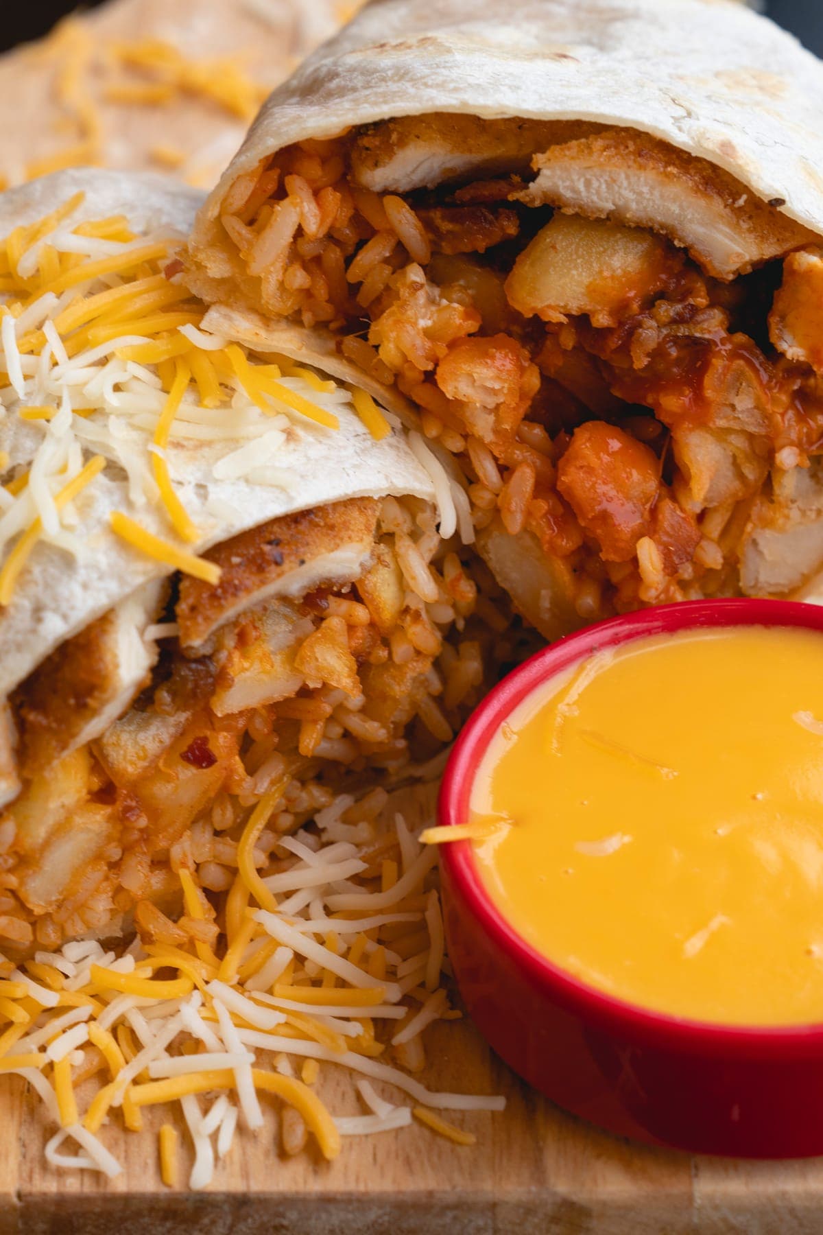 Burrito halves with queso dip and shredded cheese