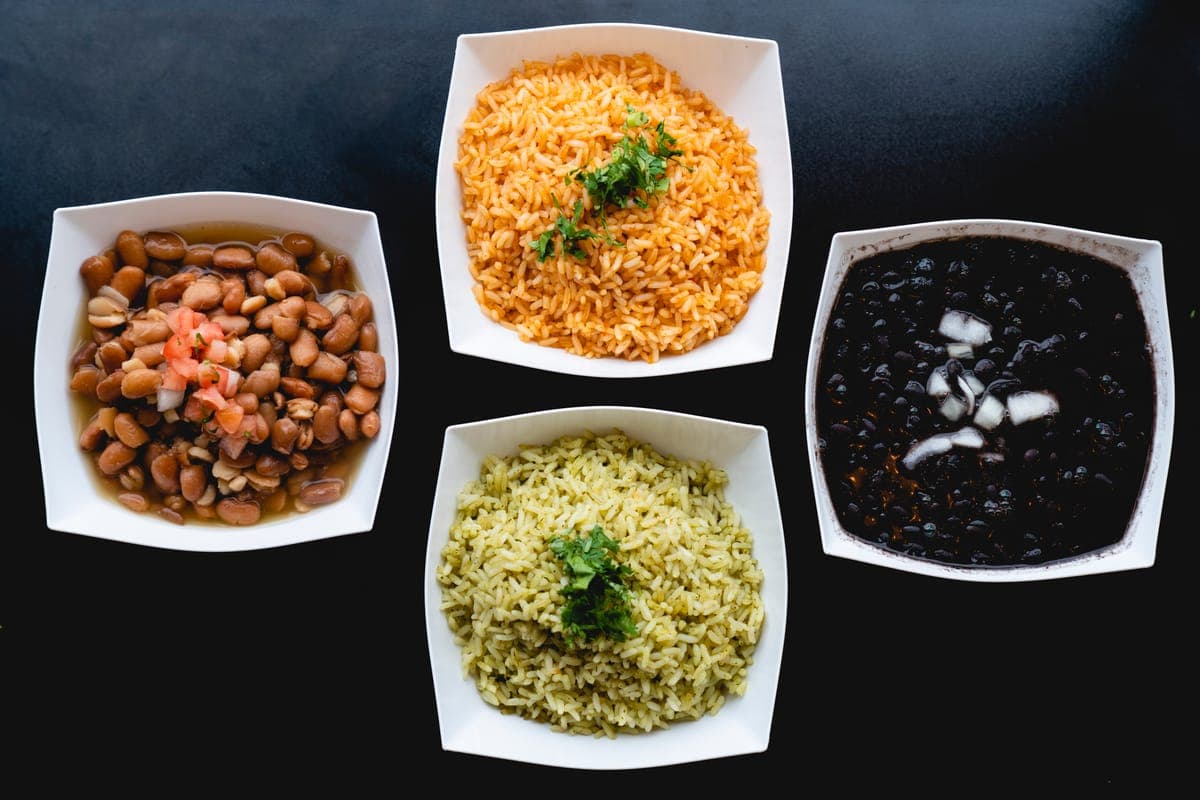 Rice, beans and sides in white bowls